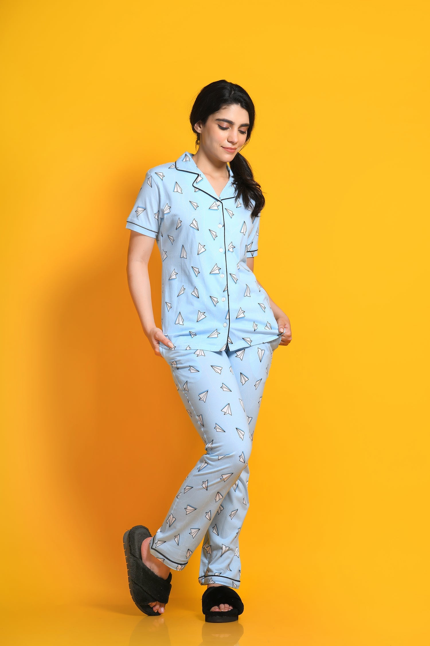 oung girl in a Paper Plane Printed Pyjama Set nightwear by NapStory, standing in style.