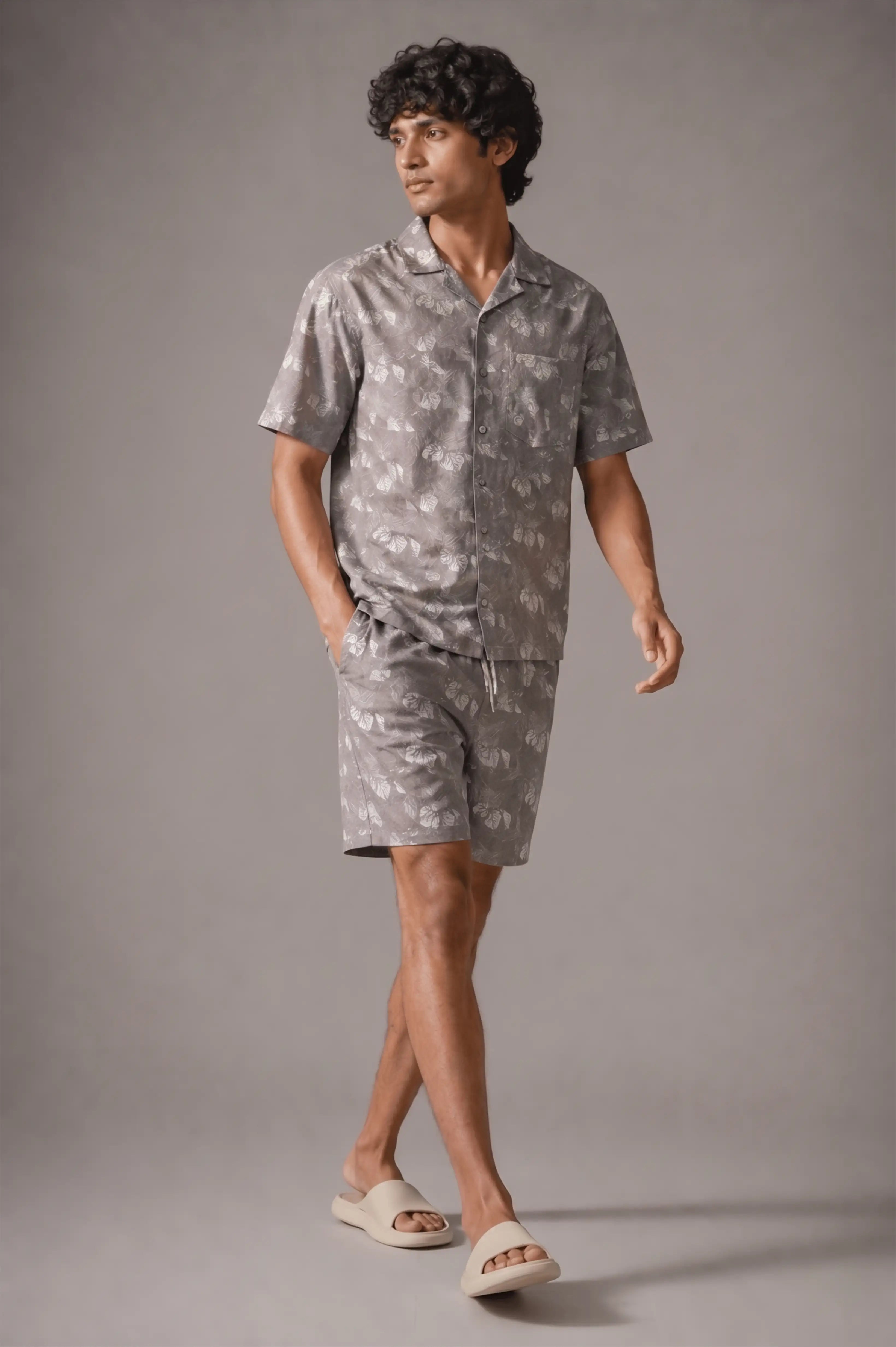 Man wearing a gray patterned shirt and shorts on a gray background