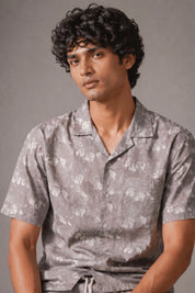 Man wearing a gray patterned shirt against a plain background