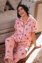 Woman wearing pink pajamas with colorful patterns sitting on a couch.