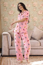 Woman wearing pink pajamas with colorful patterns in a living room.