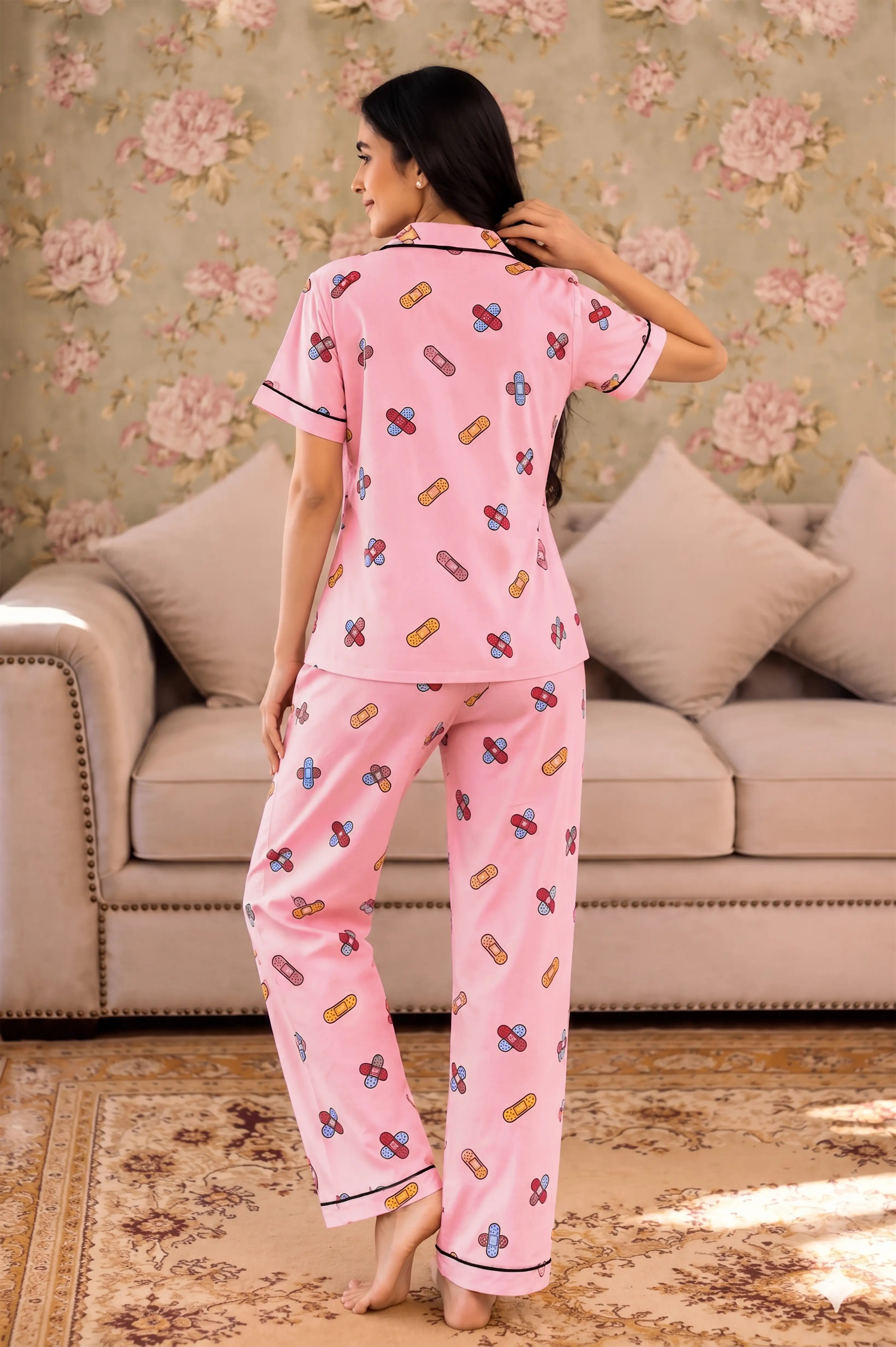 Woman wearing pink pajamas with a floral pattern in a living room.