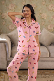 Woman wearing a pink pajama set with colorful patterns in a living room.