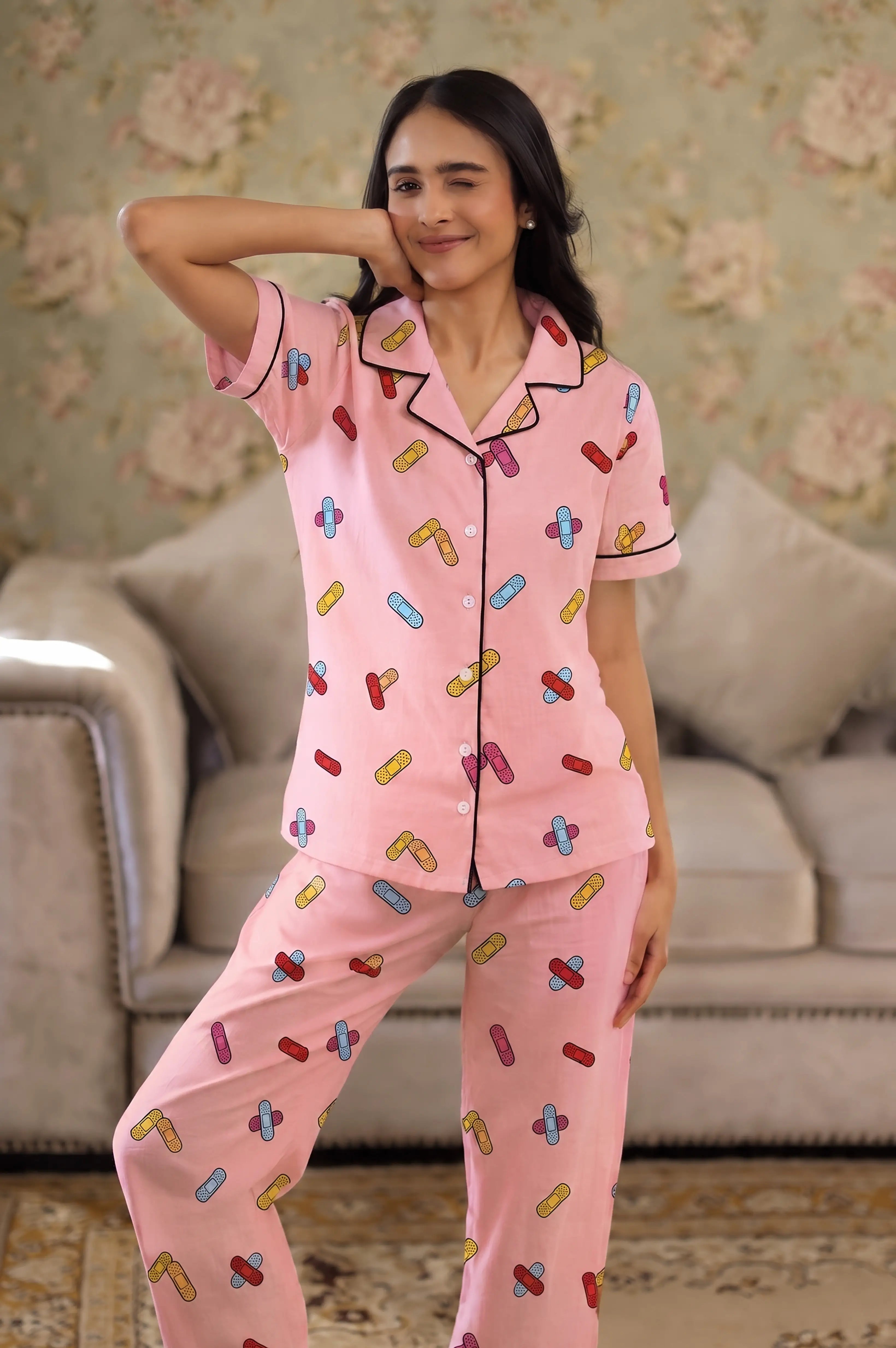 Woman wearing a pink pajama set with colorful patterns in a living room.