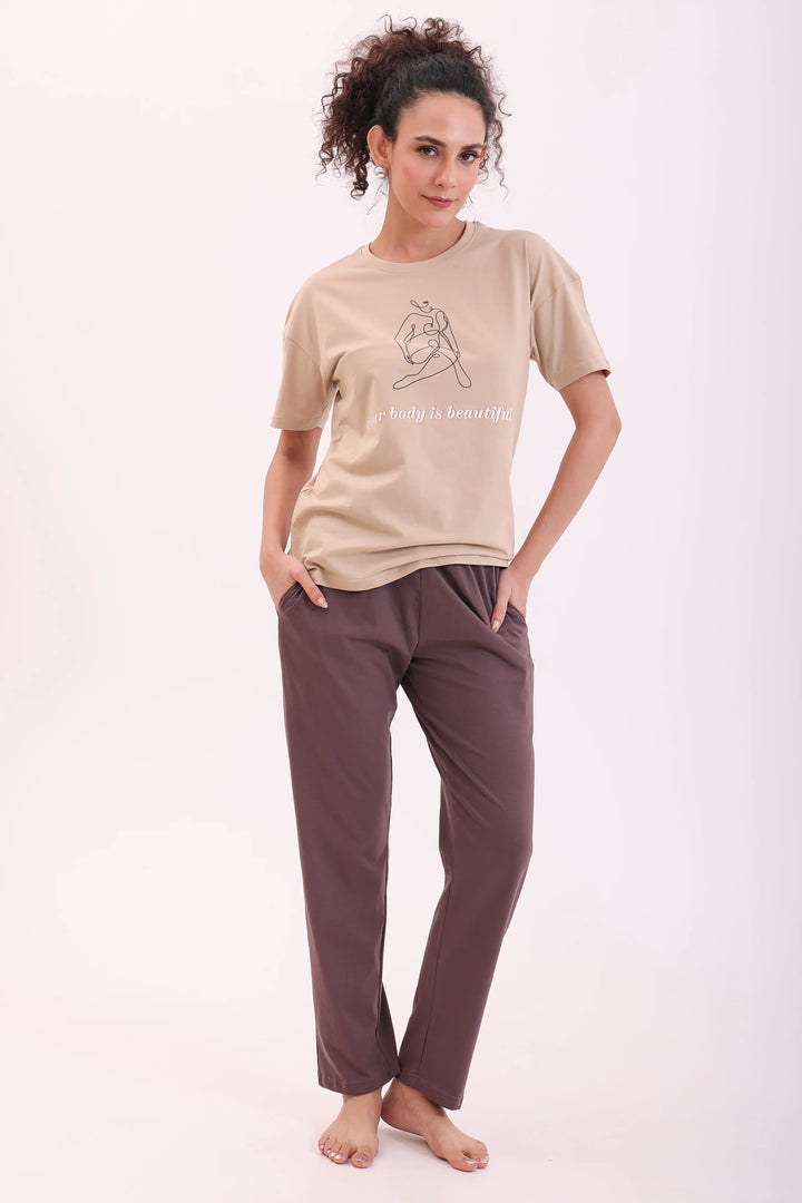 Woman standing with hands in pockets wearing sand tee & brown pyjama nightwear set by NapStory