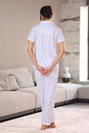 A woman wearing a patterned pajama set in a living room.