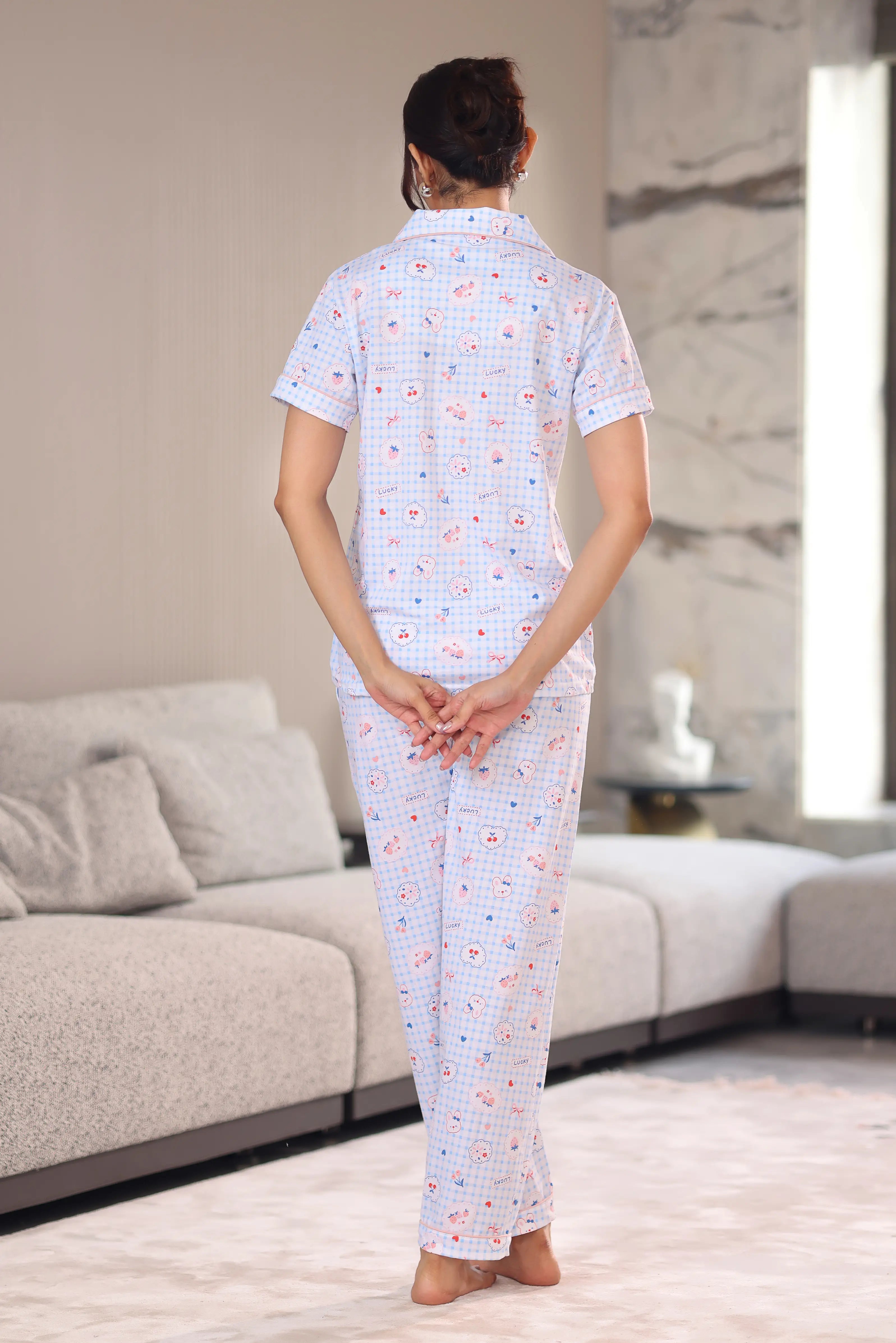 A woman wearing a patterned pajama set in a living room.