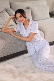 Woman in a patterned dress sitting on a gray sofa in a living room.