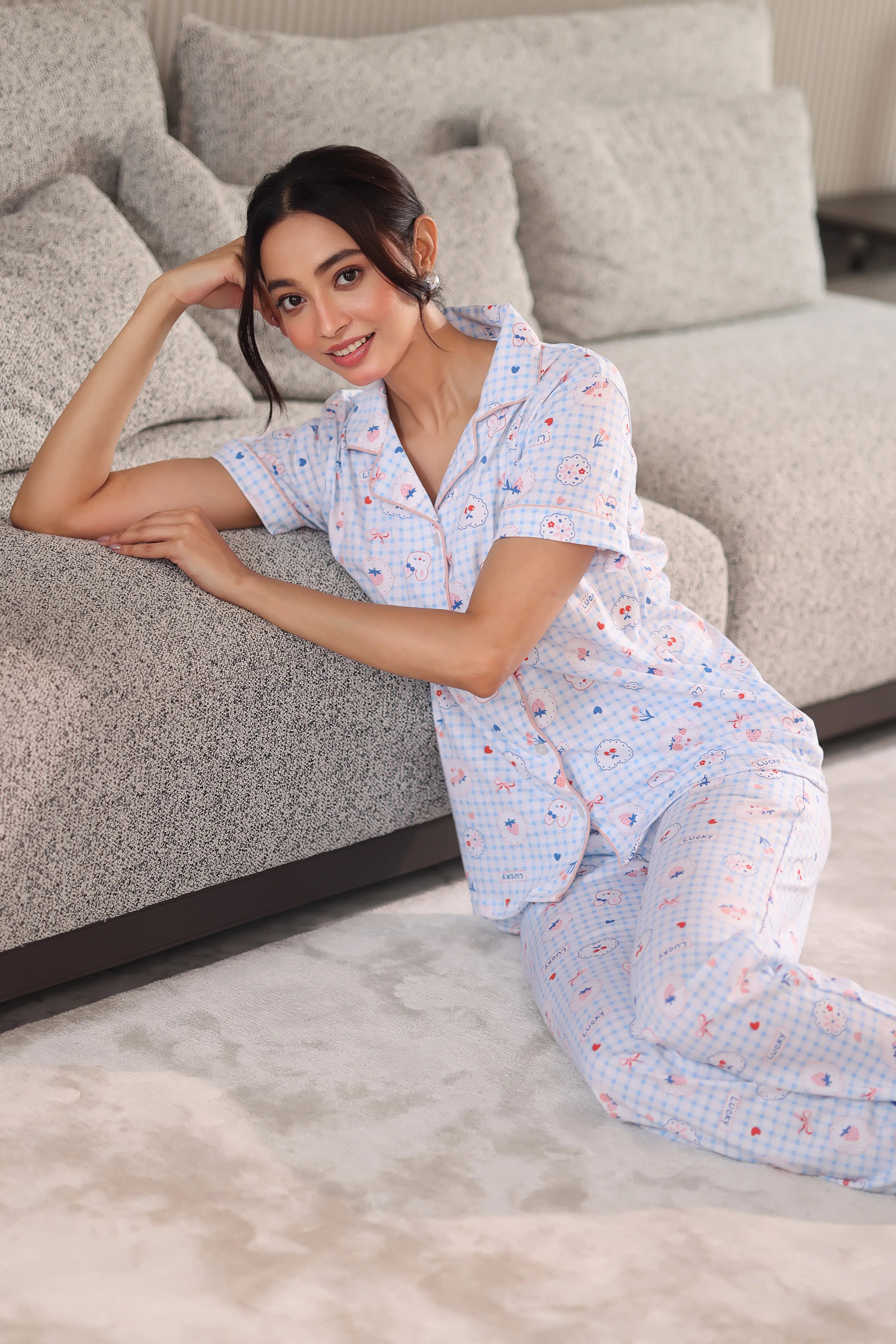 Woman in a patterned dress sitting on a gray sofa in a living room.