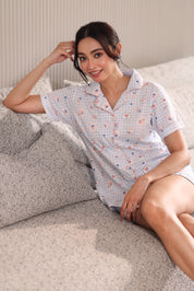 Woman wearing a patterned shorts set sitting on a couch.