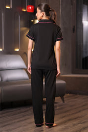 Woman wearing a black pajama set in a room with a gray sofa.