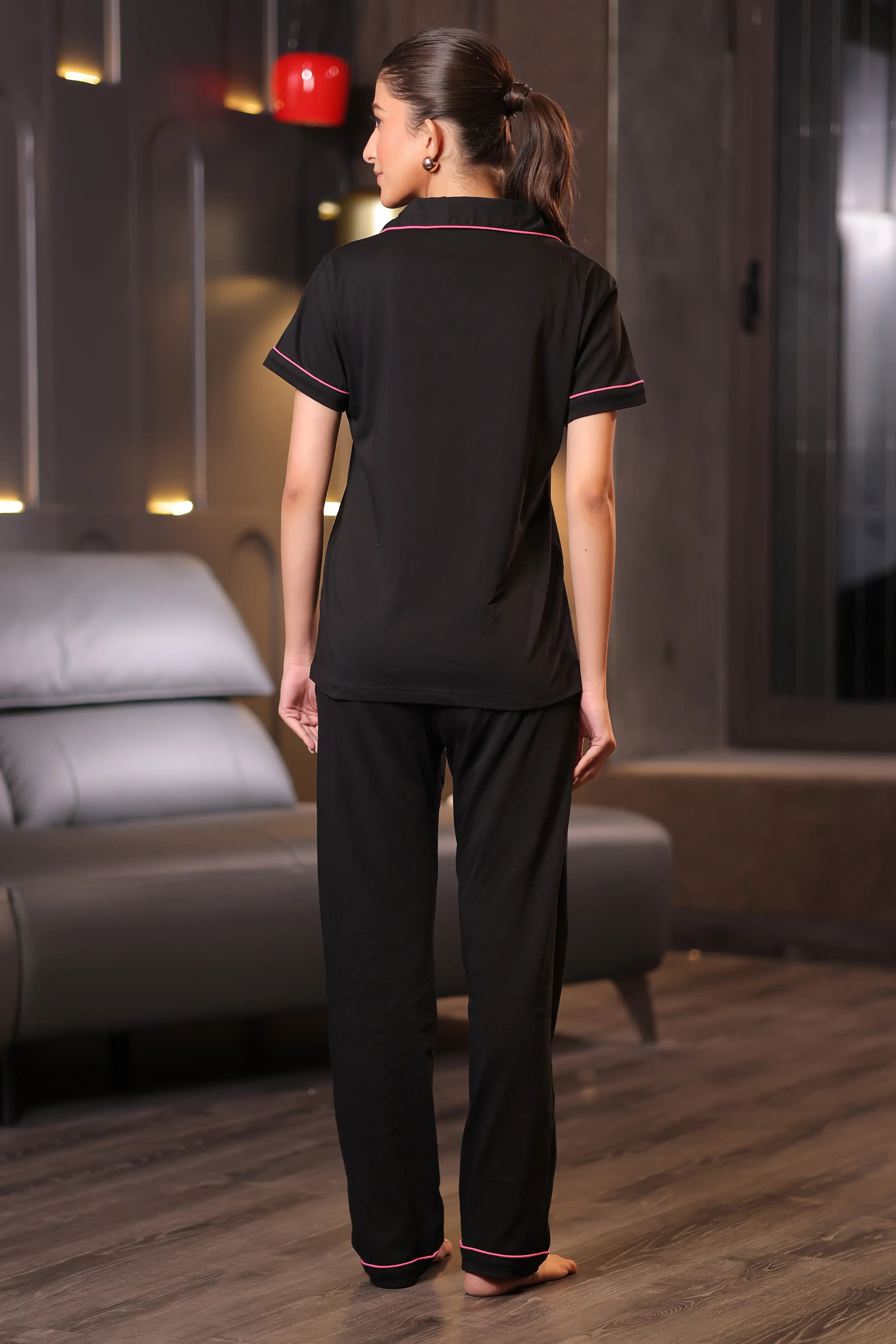 Woman wearing a black pajama set in a room with a gray sofa.