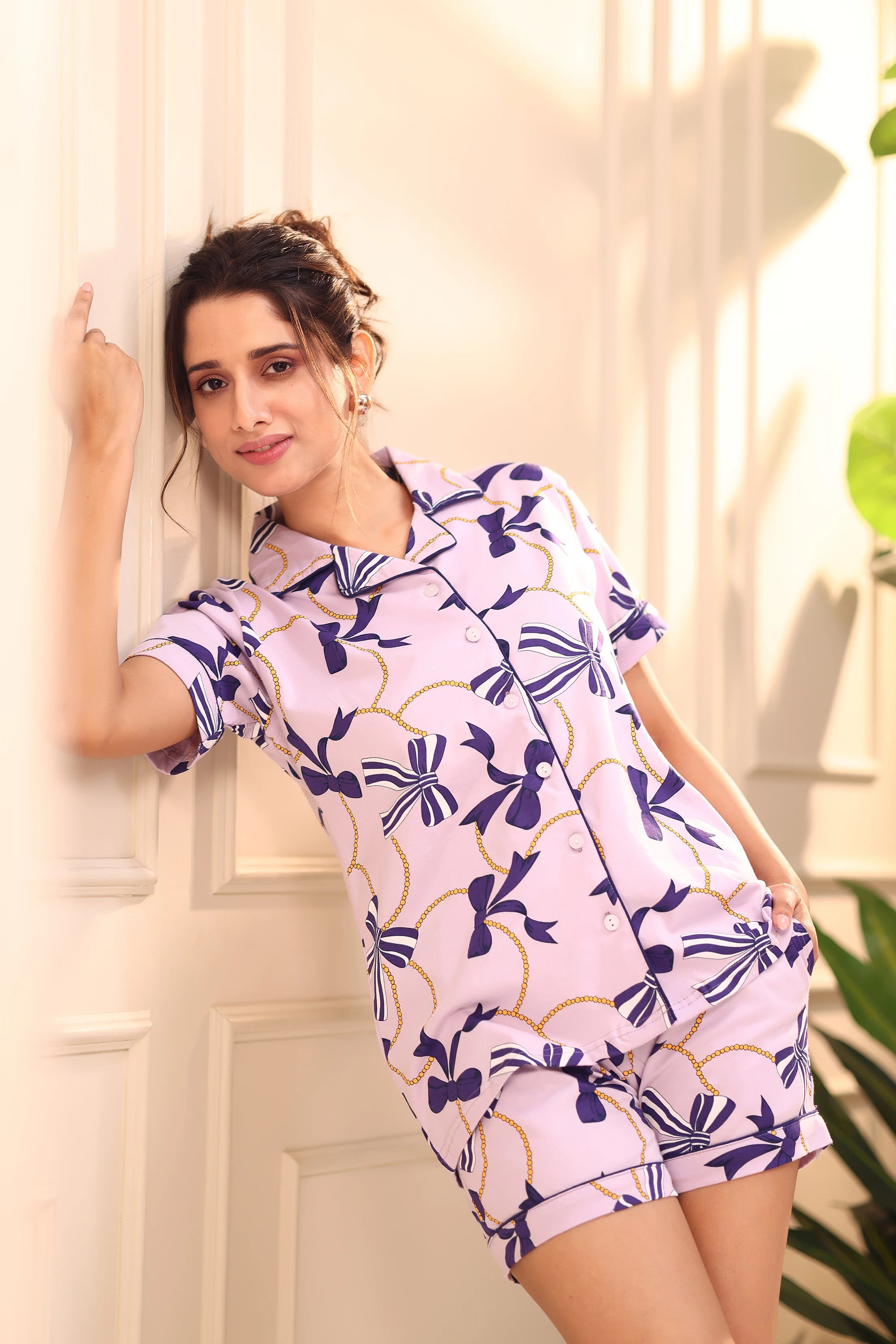Woman standing and smiling in purple bow print shorts set nightwear by NapStory.