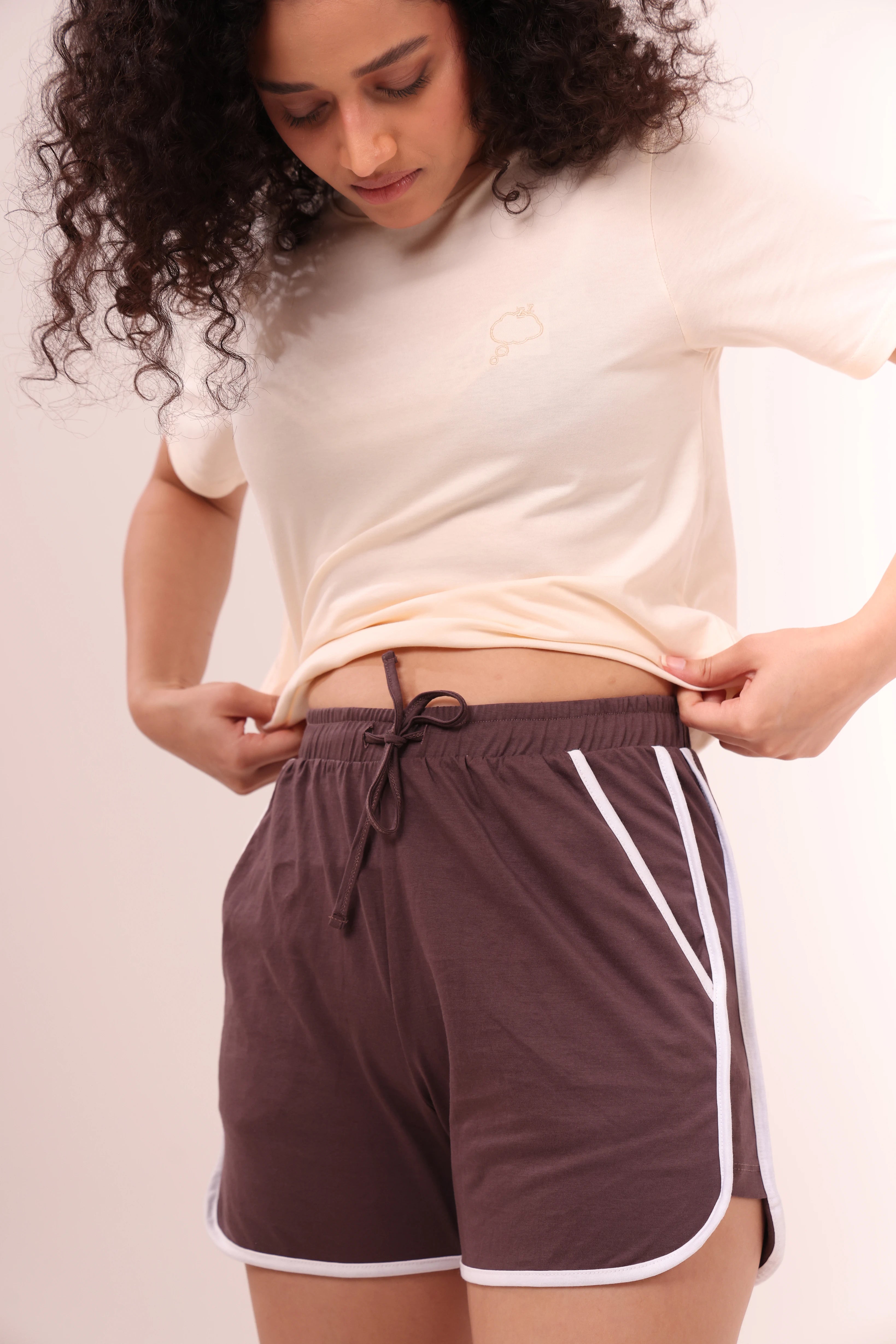 Woman adjusting brown piped-up shorts, cotton loungewear by NapStory