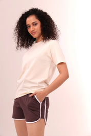 Woman posing in brown piped-up shorts and beige top, comfortable cotton loungewear by NapStory