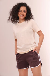 Woman smiling in brown piped-up shorts and beige cotton tee by NapStory