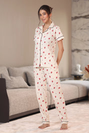 Woman wearing a white pajama set with red patterns in a living room.