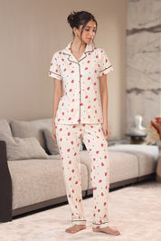 A woman wearing a pajama set with a red bug pattern in a living room.
