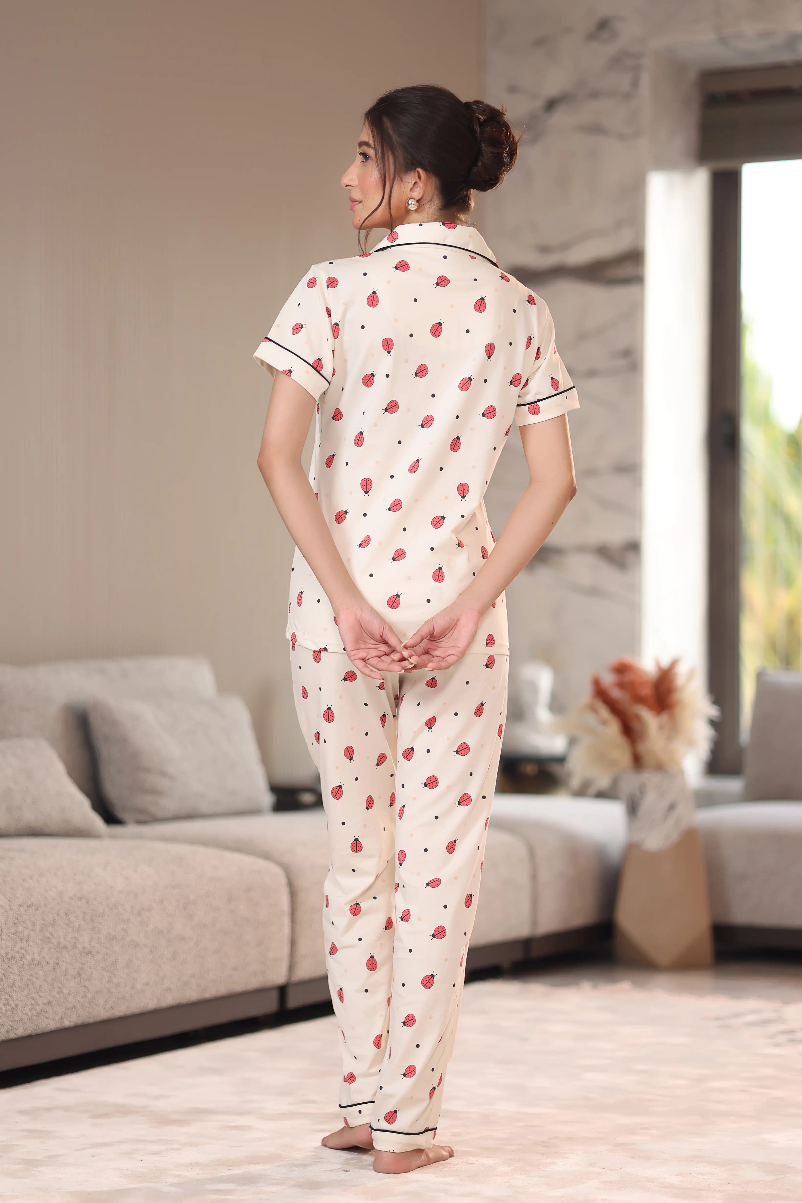 Woman wearing a patterned pajama set in a living room.