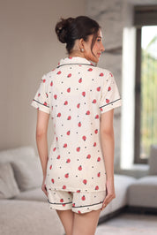 Woman wearing a white printed shorts set with bug and dot patterns in a room.