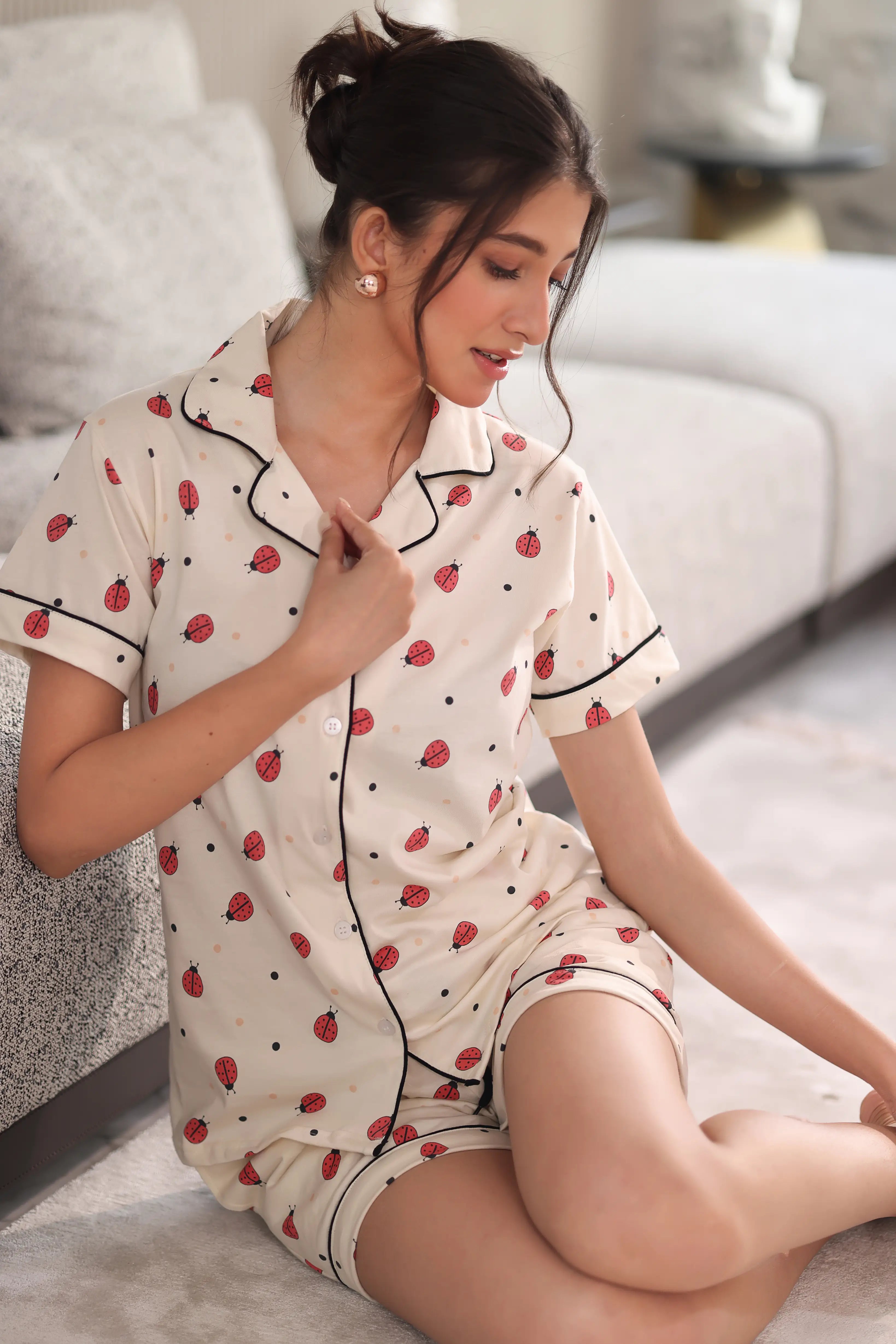 Woman wearing a shorts set with a bug pattern in a living room.