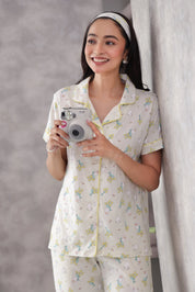 Woman in a bunny printed pajama set holding a camera against a neutral background