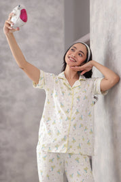 Woman in a printed pajama set holding a pink object against a gray background