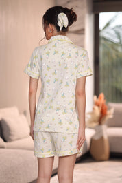 Woman wearing a light-colored printed shorts set with bunny and floral pattern in a living room.