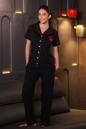 Woman wearing a black outfit with red accents in a room with decorative lighting.