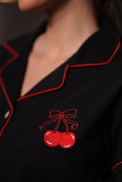 Black embroidery pyjama set with red piping and cherry embroidery design on a dark background