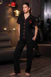Woman wearing black pajamas with red accents in a dimly lit room.