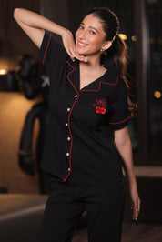 Woman wearing a black outfit with red accents in an indoor setting