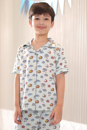 Child wearing a patterned shirt and pants set with a neutral background