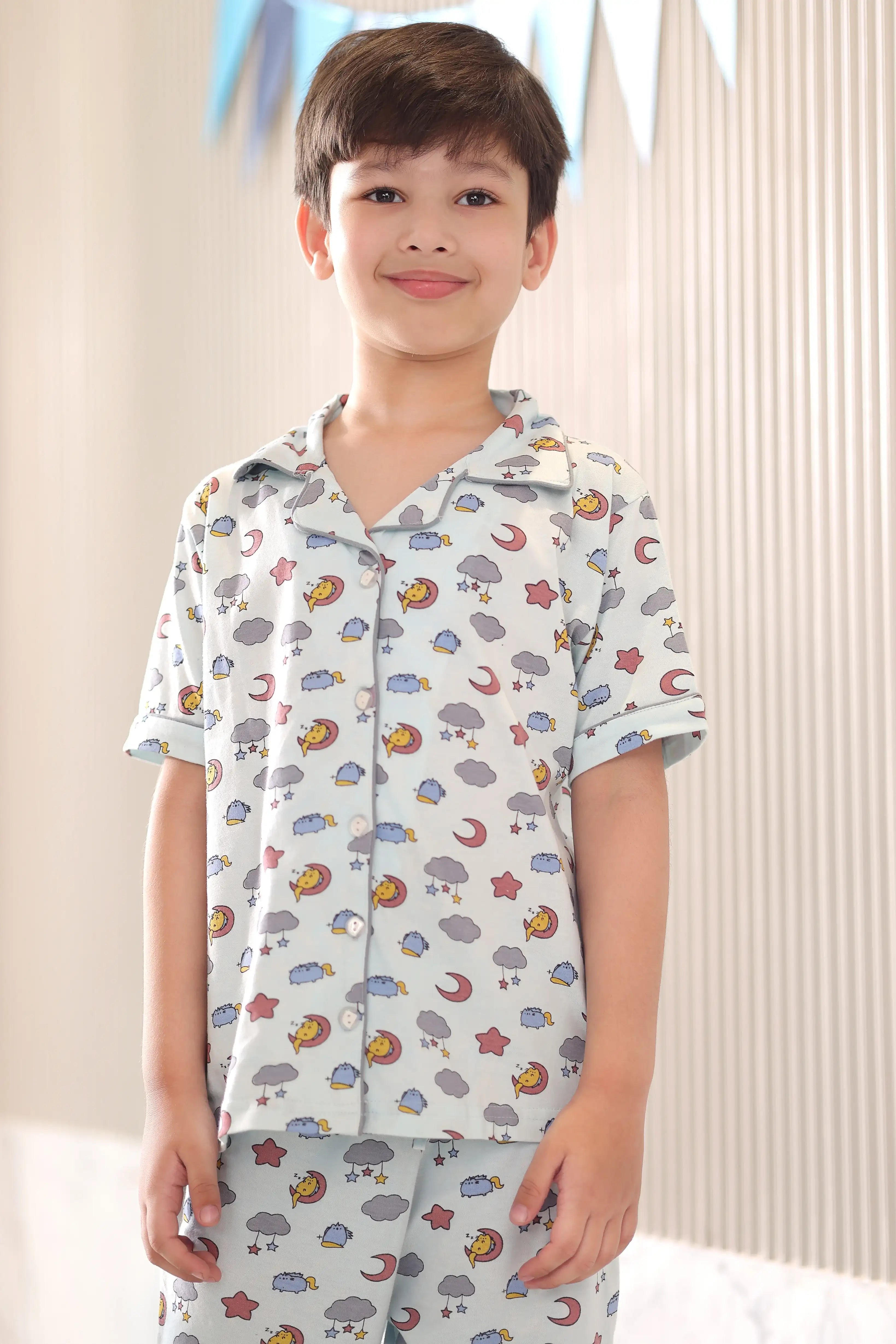 Child wearing a patterned shirt and pants set with a neutral background