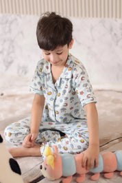 Child wearing pajamas with a pattern of cars and animals, sitting on a couch holding a toy.
