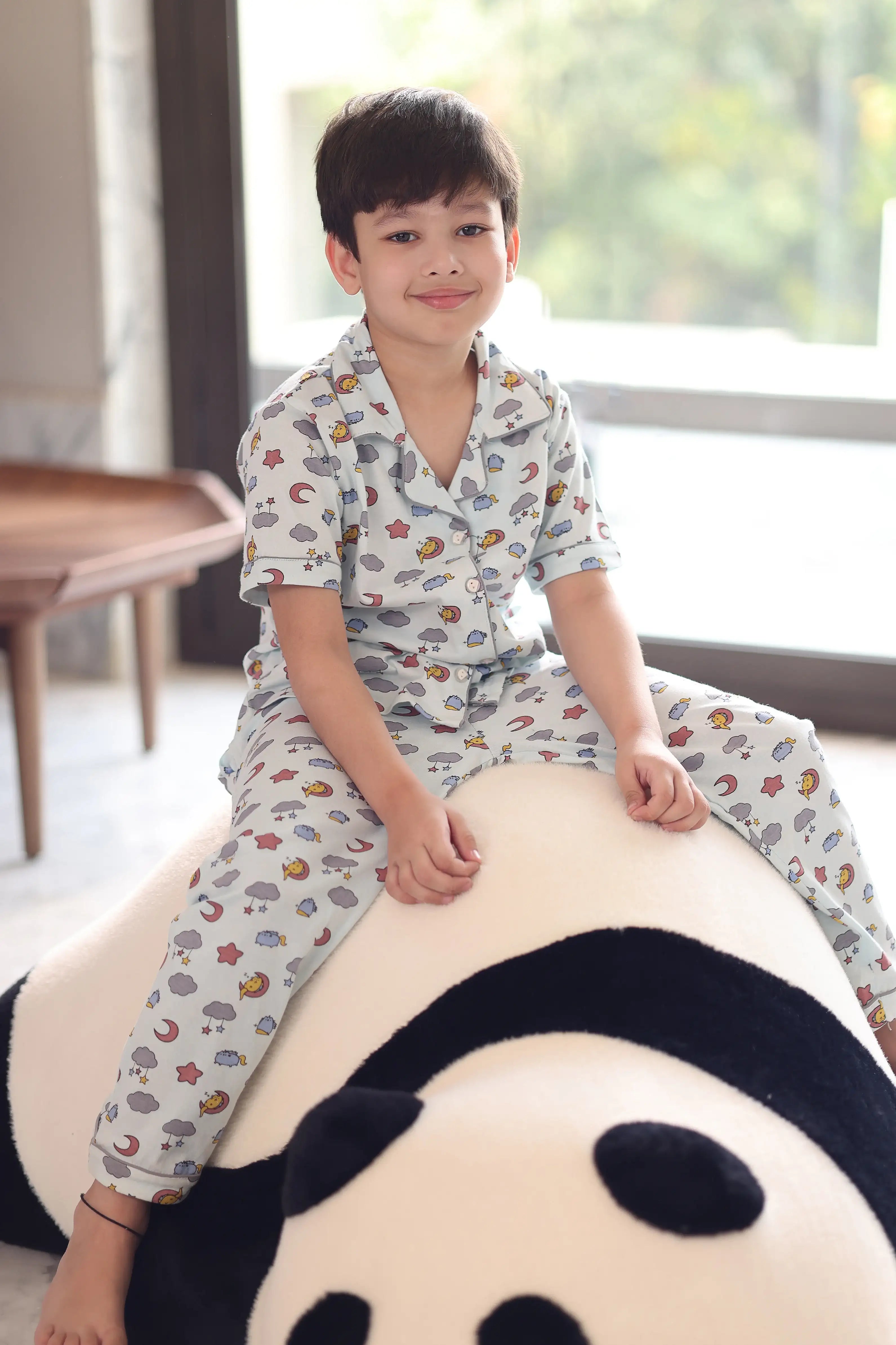 Child in a cloud print outfit, sitting on a large plush toy