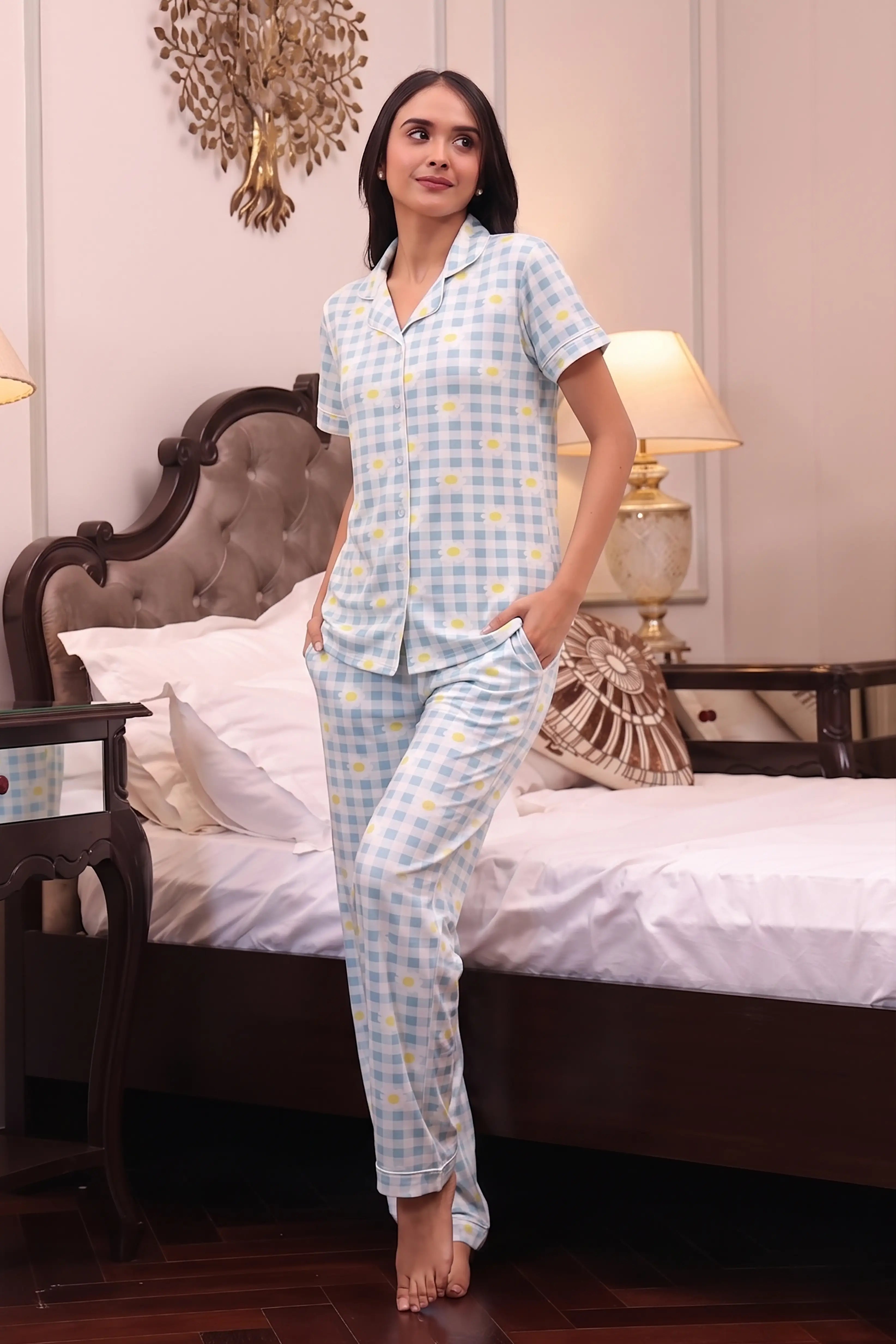 Woman wearing a light blue checkered pajama set in a bedroom.