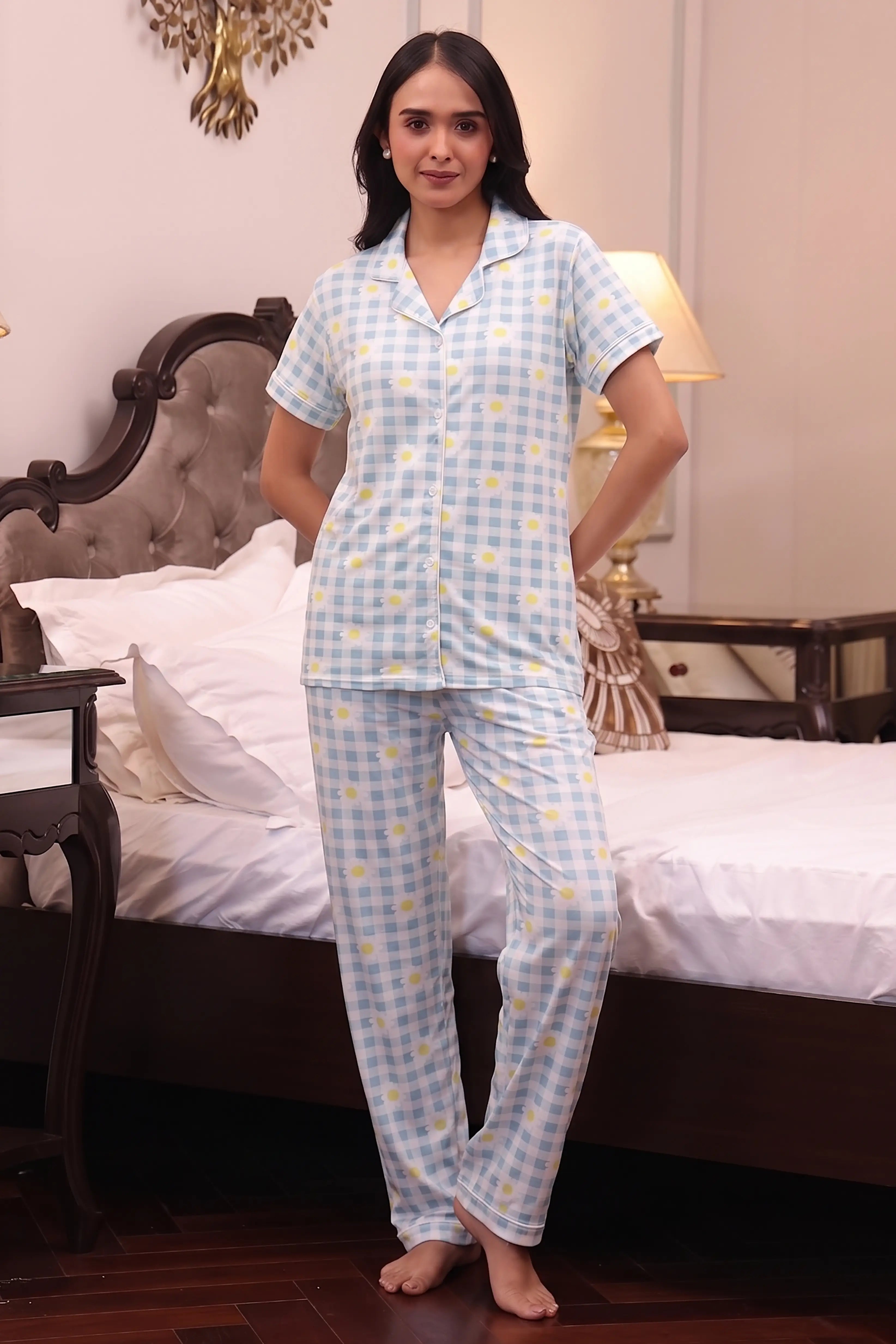 Woman wearing a blue checkered pajama set in a bedroom.