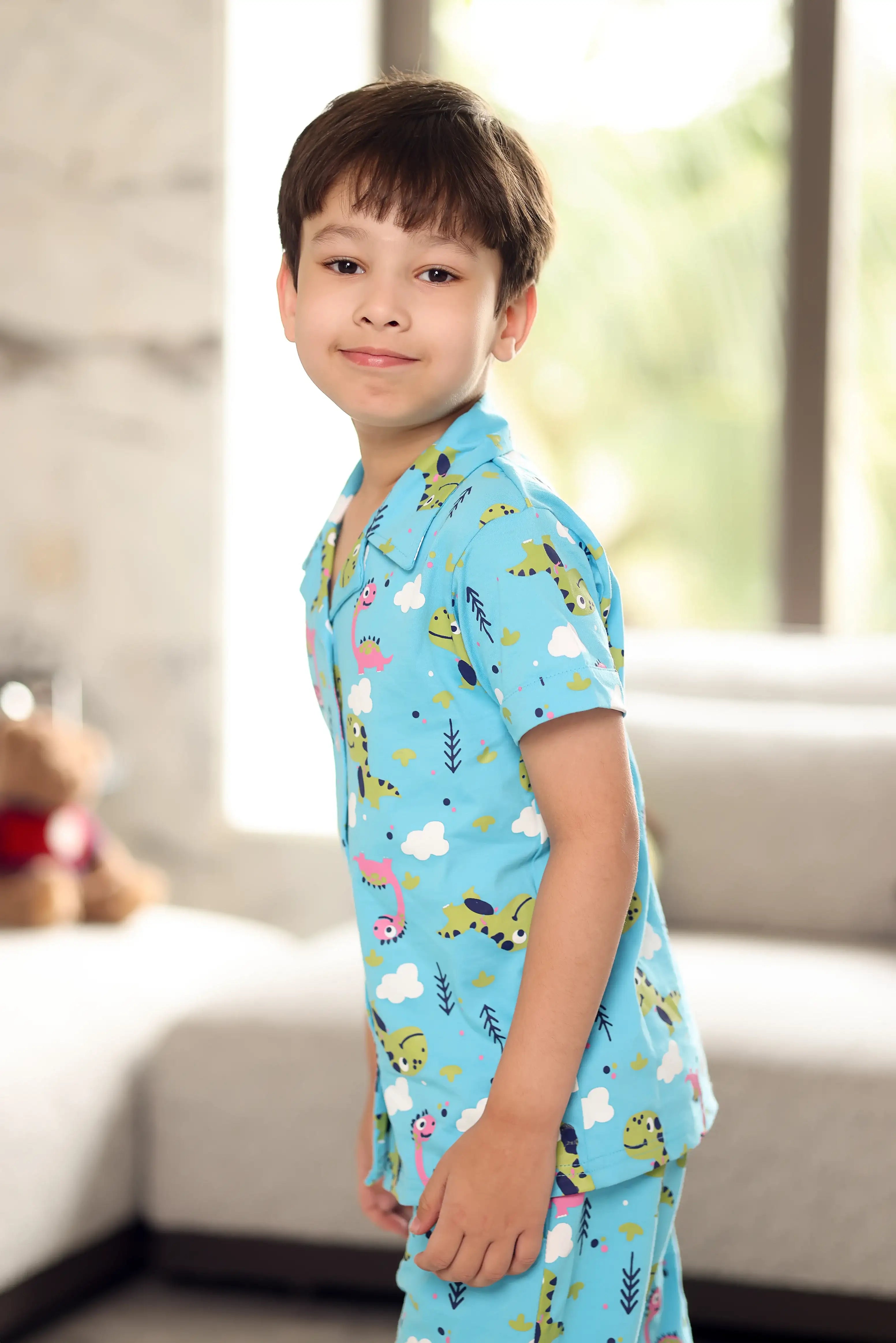 A child wearing a blue shirt with animal prints in a room.
