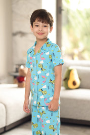 A child wearing a blue pajama set with a dinosaur pattern in a living room.