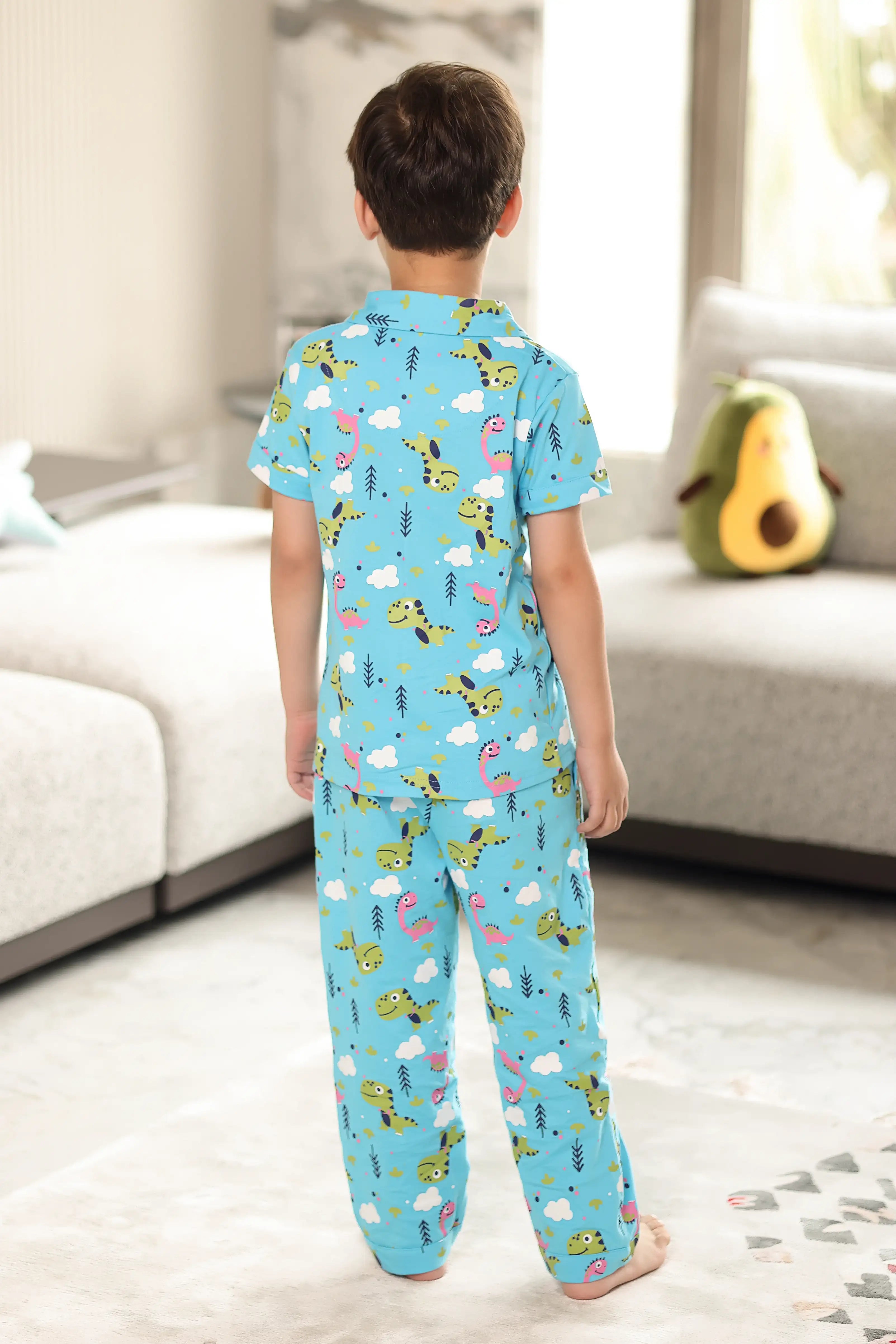 A child wearing a blue pajama set with animal prints in a living room.