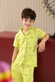 Child wearing a bright green pajama set with a dog pattern, standing indoors.