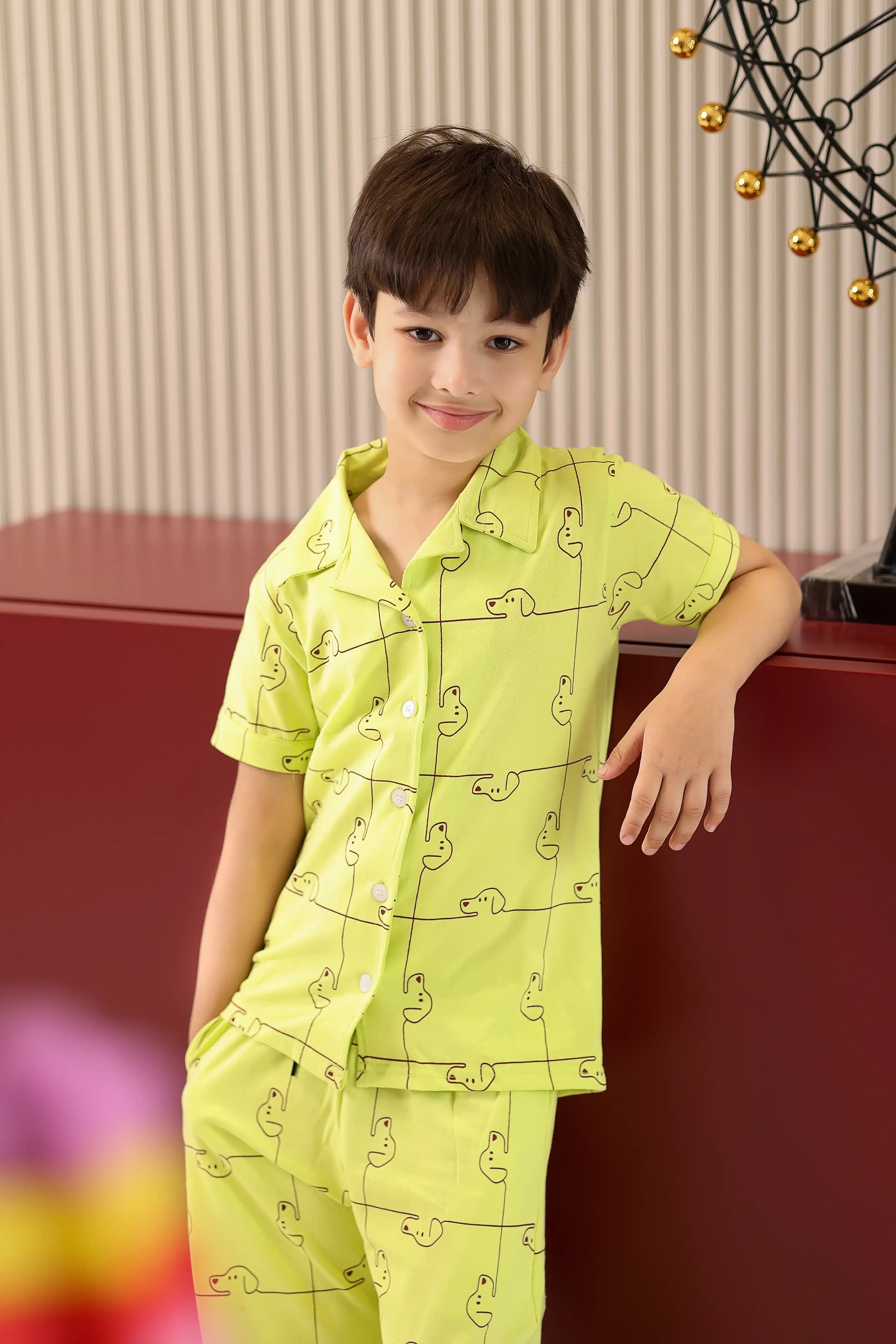 Child wearing a bright green pajama set with a dog pattern, standing indoors.