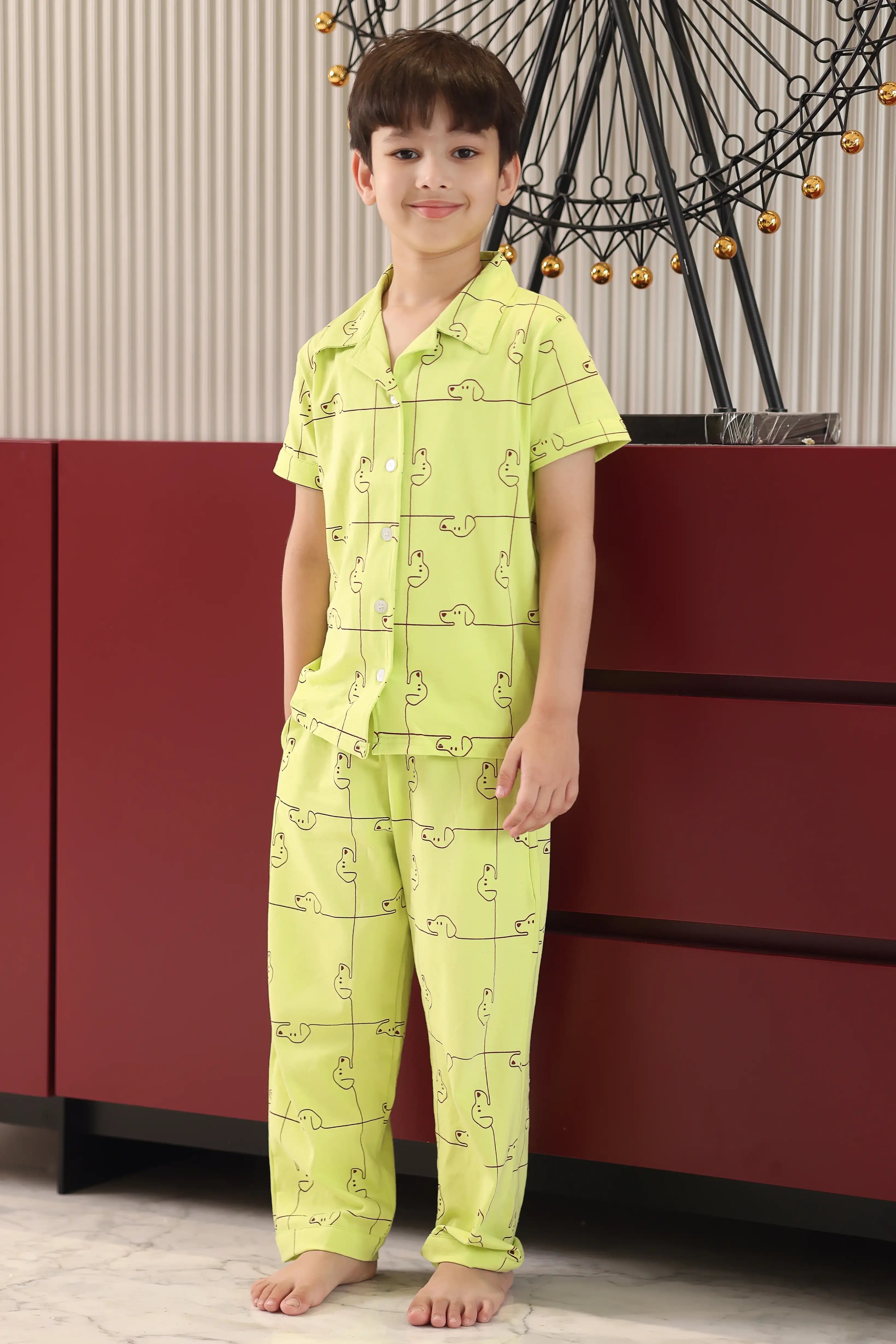Child wearing a bright green pajama set with a dog pattern in a room.