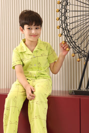 A child wearing a bright green outfit with a dog pattern, sitting on a red surface.