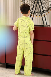 A child wearing a bright green pajama set. Standing in front of a red cabinet.