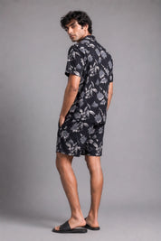 Man wearing a black floral shirt and shorts on a gray background