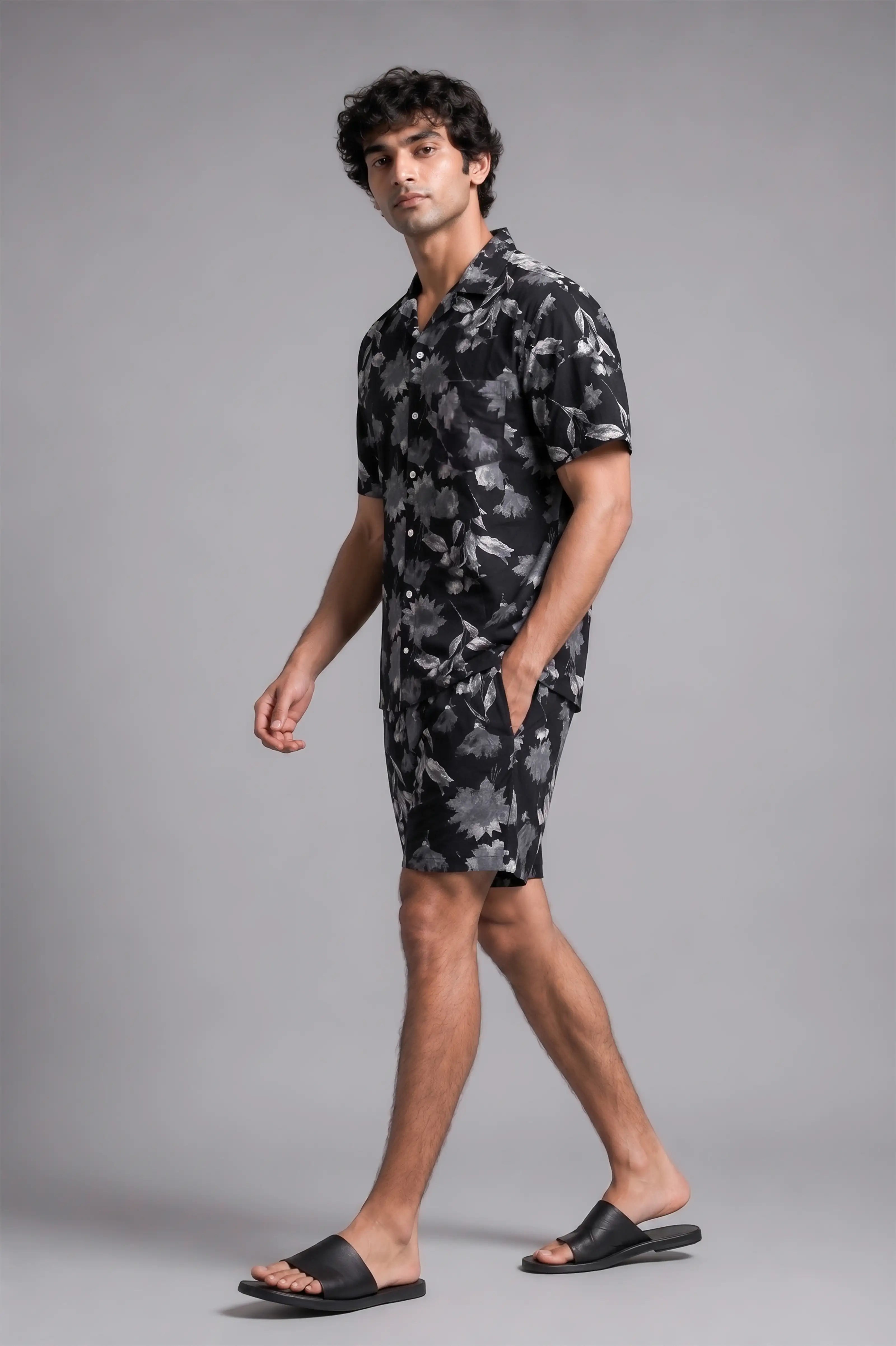 Man wearing a black and gray camouflage dress shirt and shorts on a gray background