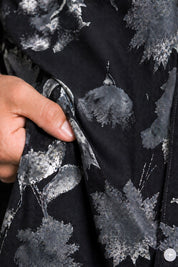 Close-up of a hand holding black fabric with gray floral patterns