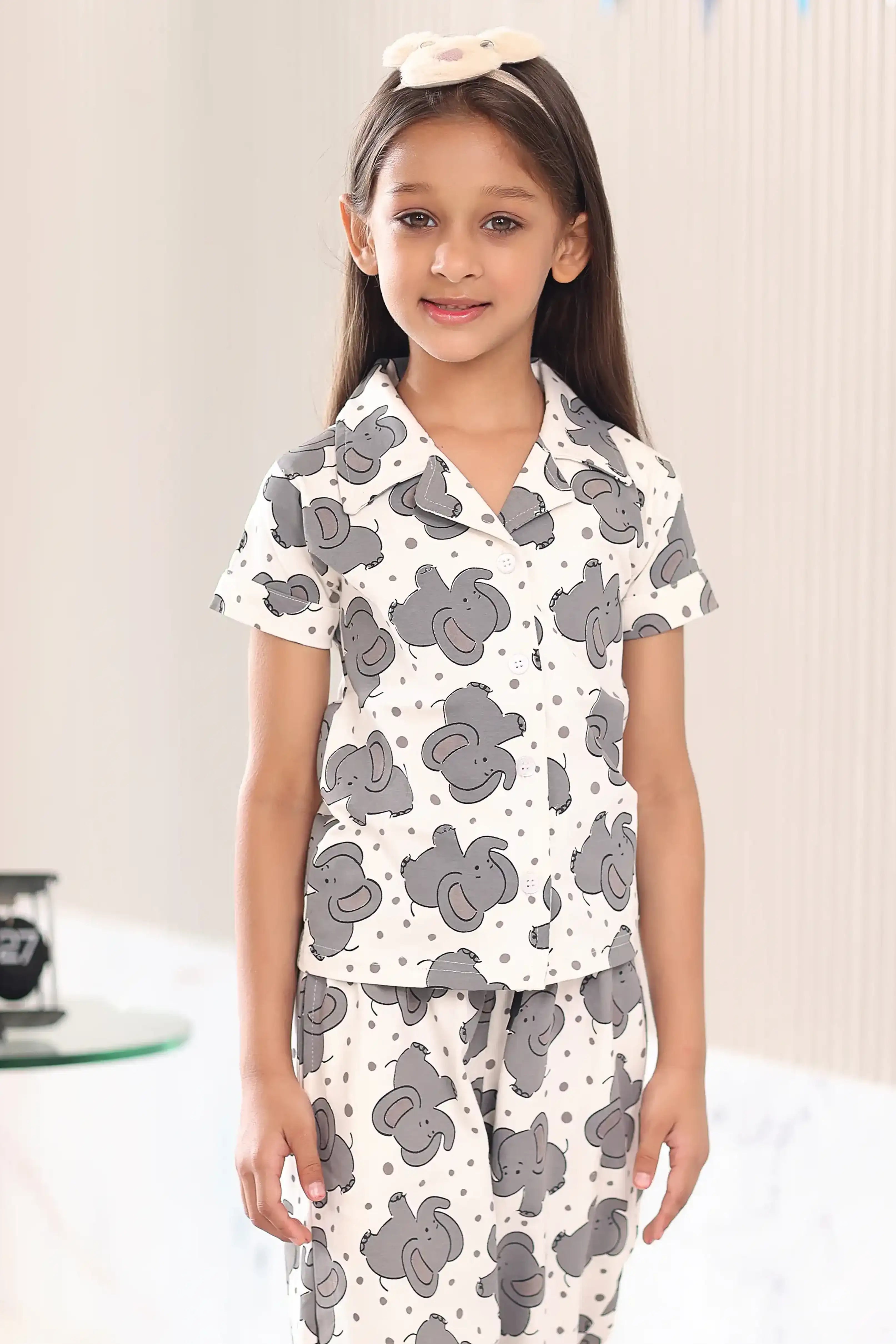 A girl wearing a pajama set with a cute elephant pattern in a bedroom setting